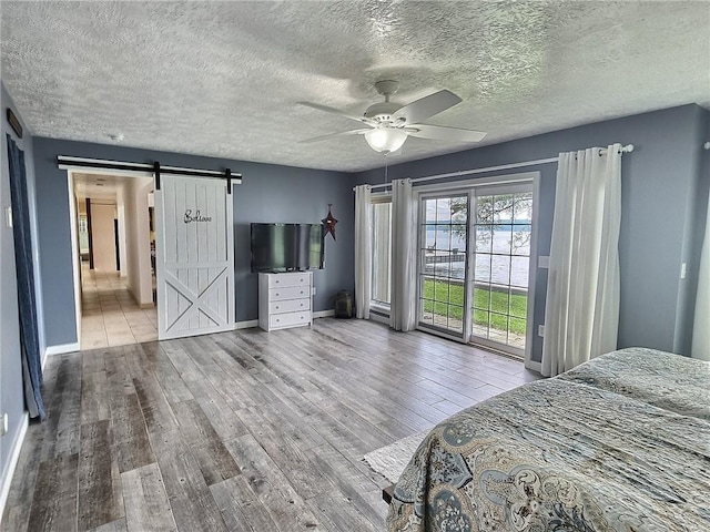 641 Fire Ln Unit 5, Genoa, NY 13081 - bedroom featuring a barn door, access to exterior, wood finished floors, ceiling fan, and a textured ceiling