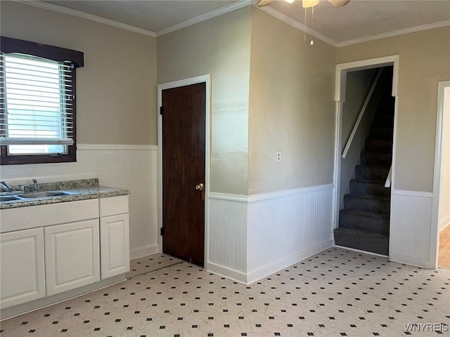 50 Ideal St, Buffalo, NY 14206 - kitchen with white cabinets, a wainscoted wall, light flooring, ornamental molding, and ceiling fan