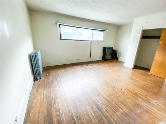 866 Smith St, Rochester, NY 14606 - unfurnished bedroom featuring radiator, hardwood / wood-style floors, a textured ceiling, and a closet