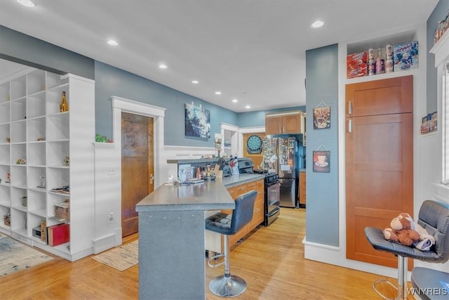 592 Parkside Ave, Buffalo, NY 14216 - kitchen featuring black range with gas stovetop, freestanding refrigerator, a kitchen breakfast bar, light wood-style flooring, and recessed lighting