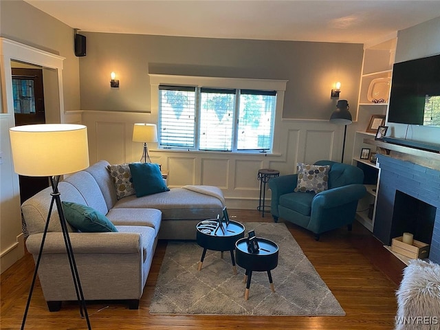 592 Parkside Ave, Buffalo, NY 14216 - living room with a decorative wall, wood finished floors, wainscoting, and a stone fireplace