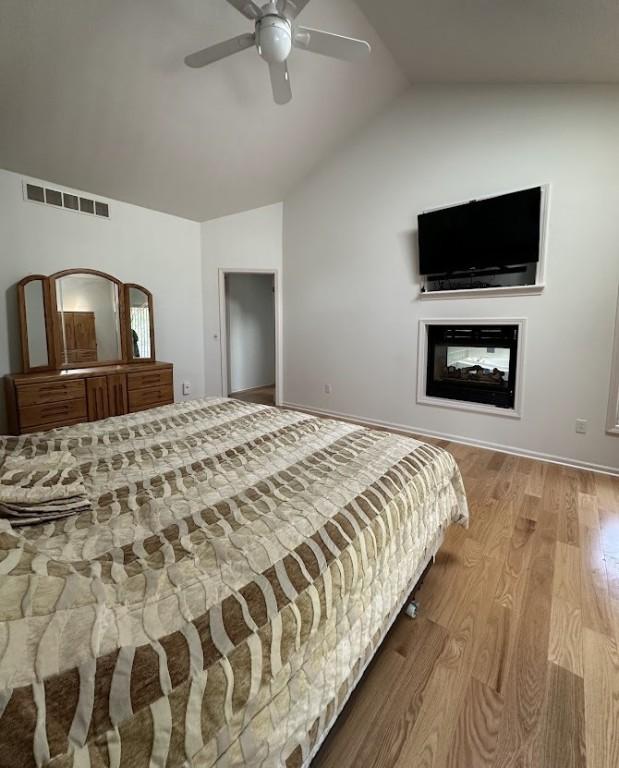 80 Endicar Dr, Irondequoit, NY 14622 - bedroom featuring lofted ceiling, wood finished floors, a ceiling fan, and a multi sided fireplace