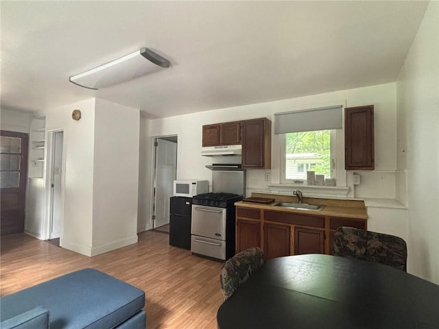 35799 State Highway 10, Hamden, NY 13782 - kitchen featuring white microwave, stainless steel gas range, under cabinet range hood, and light wood-type flooring