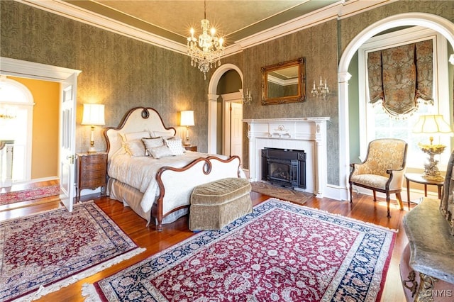 71 Forman St, Cazenovia, NY 13035 - bedroom featuring wood finished floors, arched walkways, wallpapered walls, a fireplace, and a chandelier