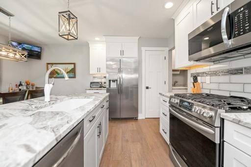 61 Kirkdale Cir, Greece, NY 14612 - kitchen with stainless steel appliances, hanging light fixtures, light wood-type flooring, white cabinetry, and backsplash