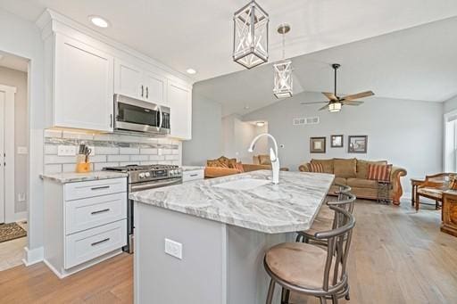 61 Kirkdale Cir, Greece, NY 14612 - kitchen with stainless steel appliances, open floor plan, light wood-type flooring, a ceiling fan, and vaulted ceiling