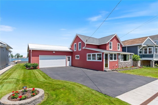8545 Greig St, Sodus, NY 14555 - traditional home featuring asphalt driveway, an attached garage, a front yard, a metal roof, and stone siding