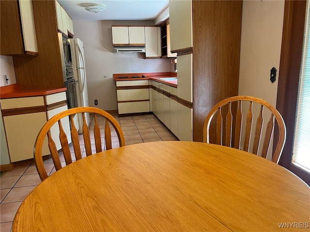 3980 Ridgelea Dr, Newfane, NY 14094 - kitchen featuring light tile patterned floors, white cabinets, freestanding refrigerator, and under cabinet range hood