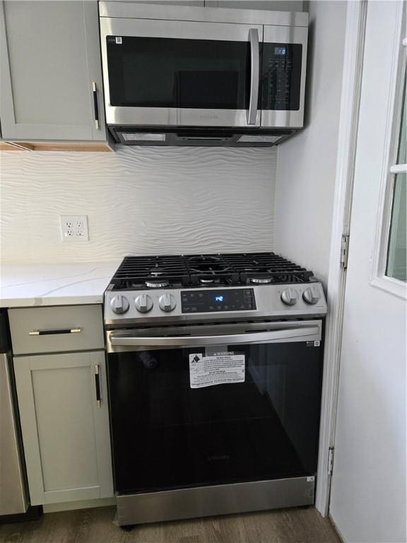 41 Garnet St, Rochester, NY 14609 - kitchen featuring appliances with stainless steel finishes, tasteful backsplash, light stone countertops, and wood finished floors