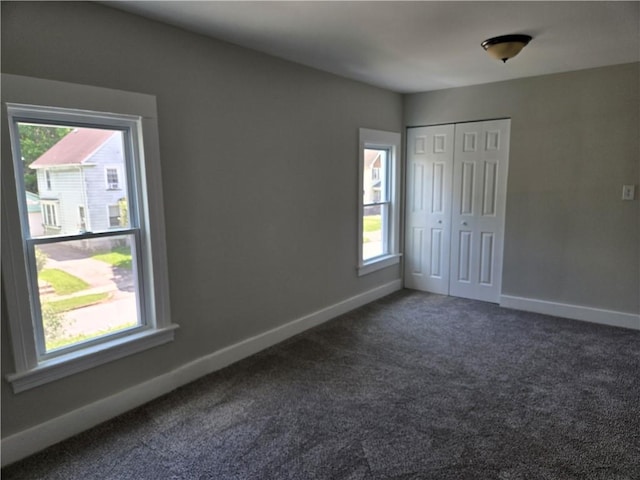 41 Garnet St, Rochester, NY 14609 - unfurnished bedroom featuring multiple windows, dark colored carpet, and a closet