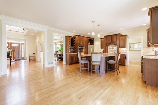 4 Crowne Pointe Dr, Penfield, NY 14526 - kitchen with stainless steel refrigerator, a kitchen breakfast bar, light wood-type flooring, brown cabinetry, and a center island