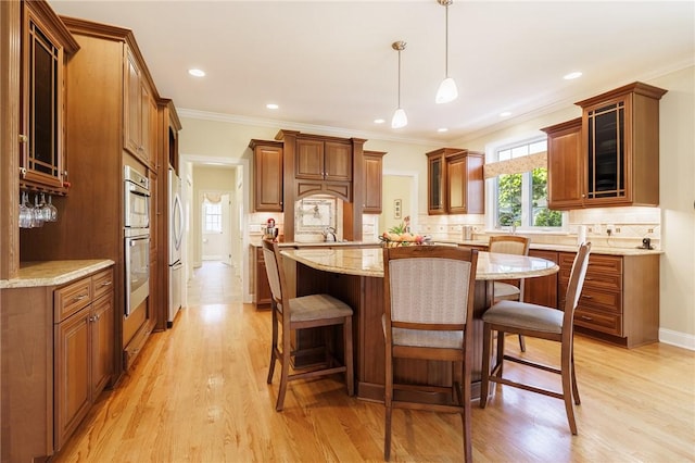 4 Crowne Pointe Dr, Penfield, NY 14526 - kitchen featuring a breakfast bar, a kitchen island, appliances with stainless steel finishes, brown cabinetry, and light wood-style floors