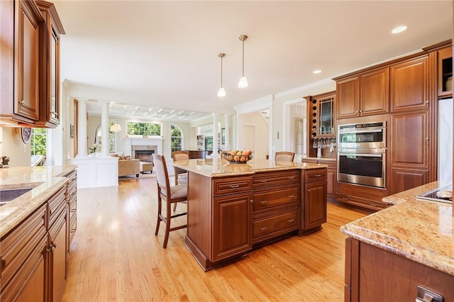4 Crowne Pointe Dr, Penfield, NY 14526 - kitchen with light wood-style floors, a breakfast bar, double oven, open floor plan, and a tiled fireplace