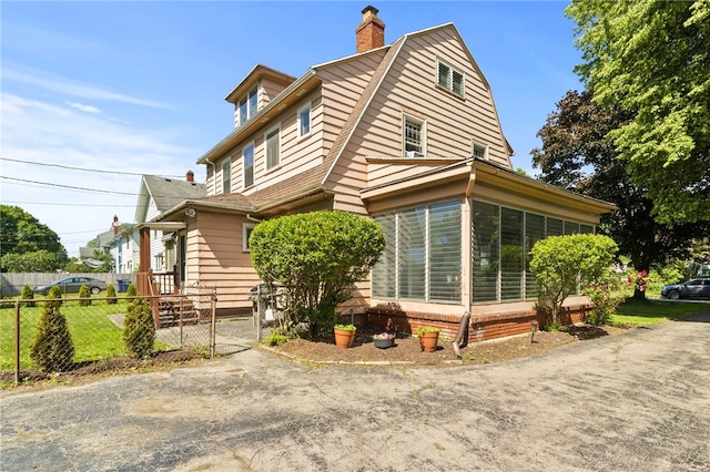 29 Stonehenge Rd, Irondequoit, NY 14609 - view of side of home with a sunroom, a chimney, and a gambrel roof