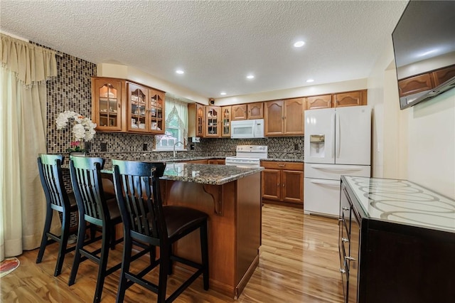 18 Chesterton Ct, Perinton, NY 14450 - kitchen featuring white appliances, a peninsula, brown cabinets, glass insert cabinets, and light wood finished floors