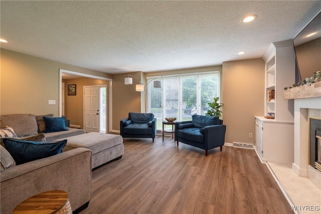 278 Shady Grove Dr, Amherst, NY 14051 - living area with a textured ceiling, wood finished floors, a tile fireplace, recessed lighting, and built in shelves