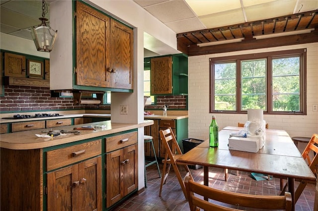 2429 English Rd, Greece, NY 14616 - kitchen featuring brick floors, light countertops, brick wall, gas stovetop, and pendant lighting