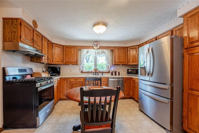 112 Pin Oak Ln, Irondequoit, NY 14622 - kitchen with stainless steel appliances, light flooring, under cabinet range hood, brown cabinetry, and light countertops