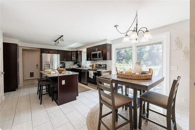 346 Willowood Dr, Greece, NY 14612 - kitchen featuring stainless steel appliances, a chandelier, dark brown cabinetry, tasteful backsplash, and a center island