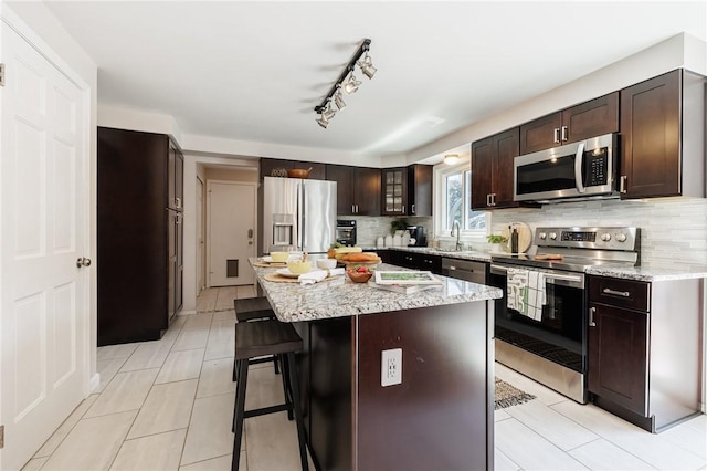 346 Willowood Dr, Greece, NY 14612 - kitchen featuring appliances with stainless steel finishes, a kitchen bar, dark brown cabinets, and backsplash