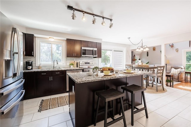346 Willowood Dr, Greece, NY 14612 - kitchen with appliances with stainless steel finishes, backsplash, a kitchen breakfast bar, and plenty of natural light