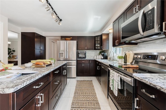 346 Willowood Dr, Greece, NY 14612 - kitchen featuring appliances with stainless steel finishes, decorative backsplash, light stone counters, light tile patterned floors, and dark brown cabinetry