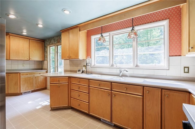 500 Pine Grove Ave, Irondequoit, NY 14617 - kitchen featuring decorative backsplash, wallpapered walls, light countertops, decorative light fixtures, and stainless steel refrigerator