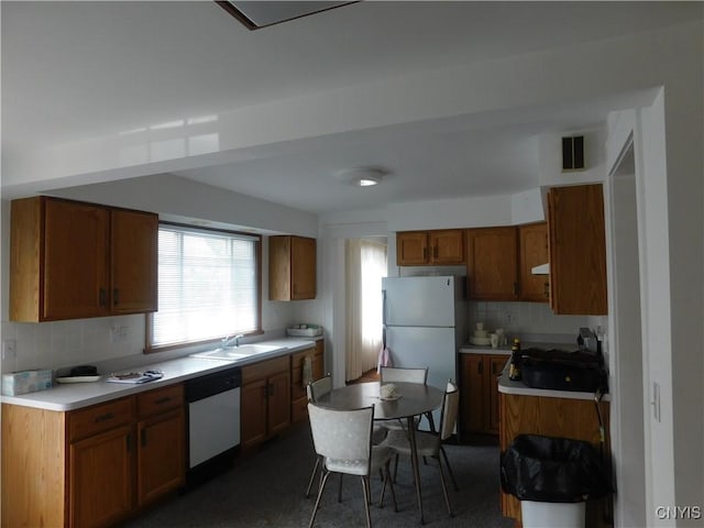 205 Shotwell Park Unit 100, Syracuse, NY 13206 - kitchen with dishwasher, freestanding refrigerator, backsplash, light countertops, and brown cabinetry