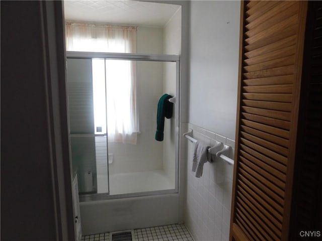 205 Shotwell Park Unit 100, Syracuse, NY 13206 - bathroom featuring tile walls, tile patterned flooring, shower / bath combination with glass door, and a wainscoted wall