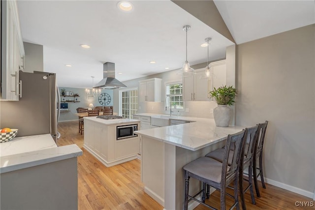 5269 Medasano Cir, Clay, NY 13041 - kitchen with island exhaust hood, stainless steel appliances, white cabinets, backsplash, and light wood-style floors
