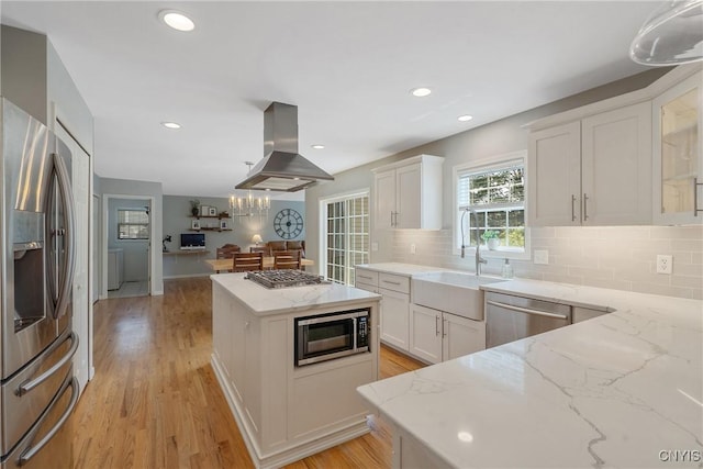 5269 Medasano Cir, Clay, NY 13041 - kitchen with appliances with stainless steel finishes, island exhaust hood, decorative backsplash, a center island, and white cabinetry