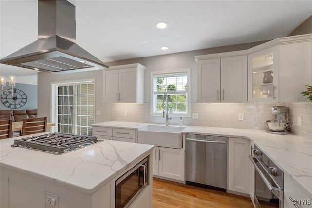 5269 Medasano Cir, Clay, NY 13041 - kitchen with appliances with stainless steel finishes, island exhaust hood, white cabinets, light wood finished floors, and light stone counters