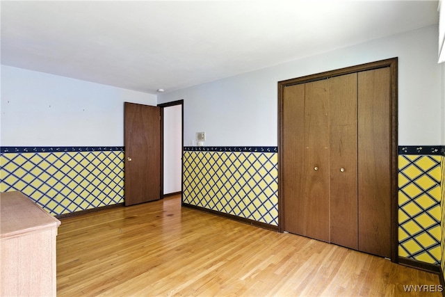 53 Christine Dr, Amherst, NY 14228 - unfurnished bedroom with light wood-style floors, a wainscoted wall, and a closet