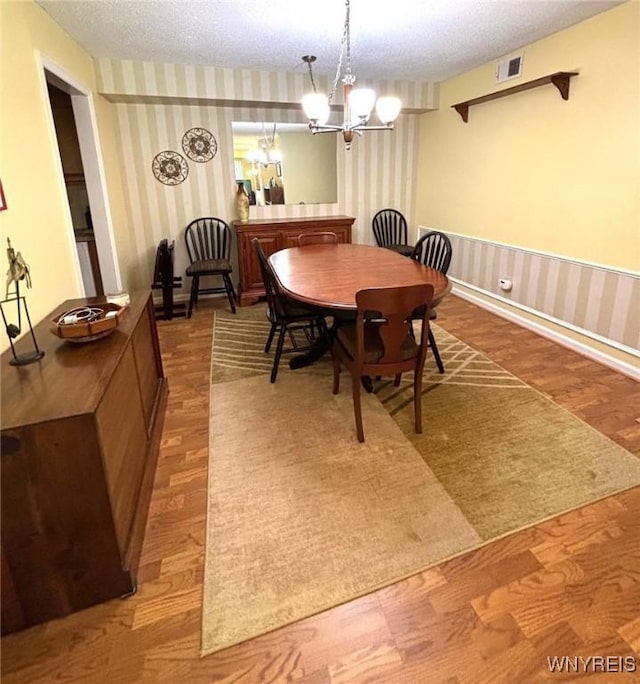 3 Homer Ln Unit B, Amherst, NY 14221 - dining space featuring wallpapered walls, a textured ceiling, a chandelier, wood finished floors, and a wainscoted wall