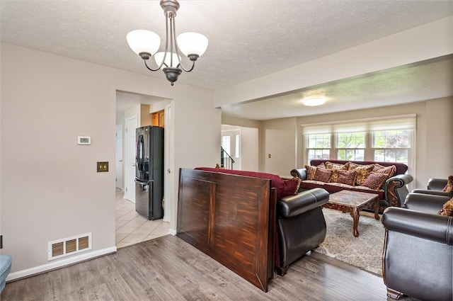 73 Hazel Bark Run, Gates, NY 14606 - living area with a chandelier, a textured ceiling, and light wood-type flooring