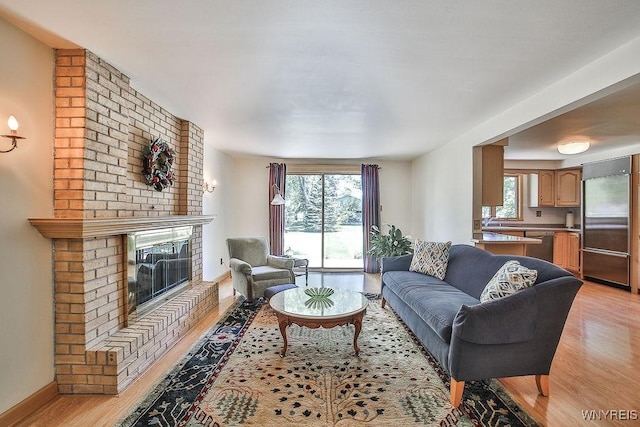 79 Pin Oak Cir, Grand Island, NY 14072 - living area featuring light wood-type flooring, a brick fireplace, and healthy amount of natural light