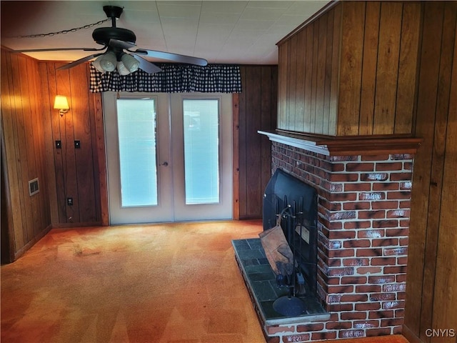 15 Beaver St, Manheim, NY 13329 - unfurnished living room with a ceiling fan, a wood stove, light colored carpet, wooden walls, and french doors