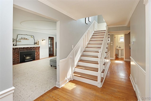 105 Maple Dr, Dewitt, NY 13066 - stairway with wood finished floors, crown molding, and a brick fireplace