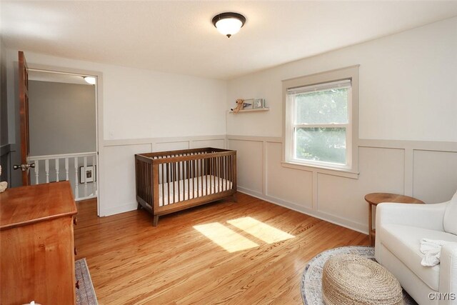 105 Maple Dr, Dewitt, NY 13066 - bedroom with wood finished floors, a wainscoted wall, a decorative wall, and a nursery area