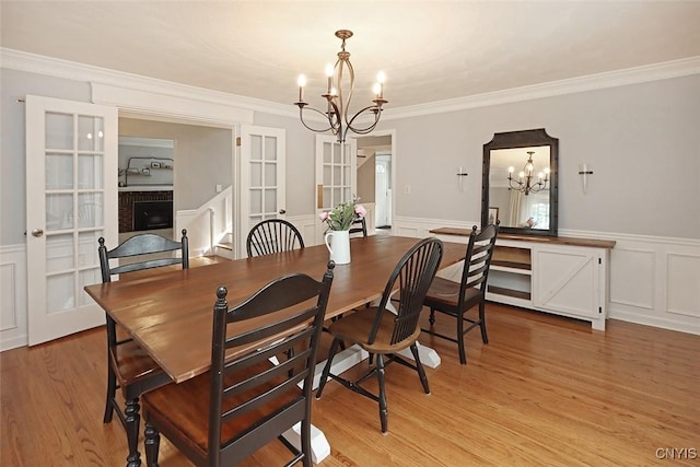 105 Maple Dr, Dewitt, NY 13066 - dining room with a chandelier, a decorative wall, french doors, light wood-type flooring, and wainscoting