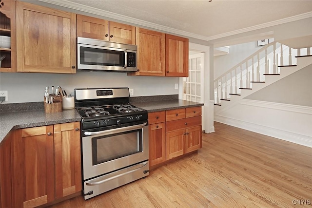 105 Maple Dr, Dewitt, NY 13066 - kitchen with stainless steel appliances, ornamental molding, light wood-type flooring, dark countertops, and brown cabinetry