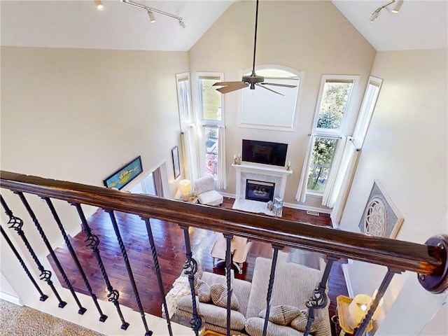 3409 Fieldstone Ln, Erwin, NY 14870 - living room featuring rail lighting, high vaulted ceiling, a glass covered fireplace, ceiling fan, and stairs