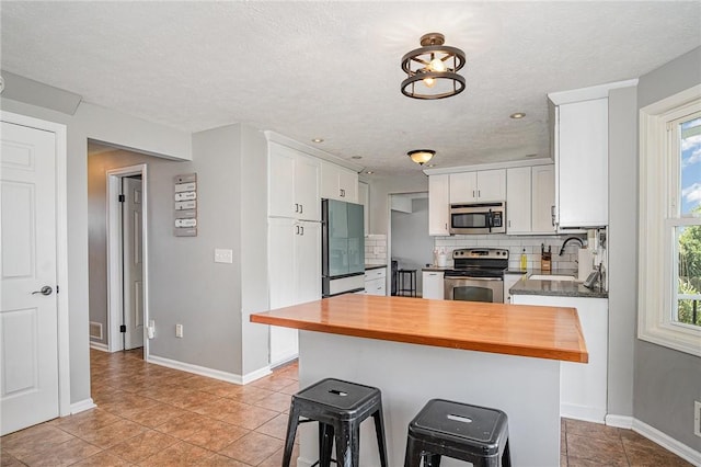 3487 Scenic Way, Walworth, NY 14502 - kitchen featuring stainless steel appliances, wood counters, white cabinets, decorative backsplash, and light tile patterned floors