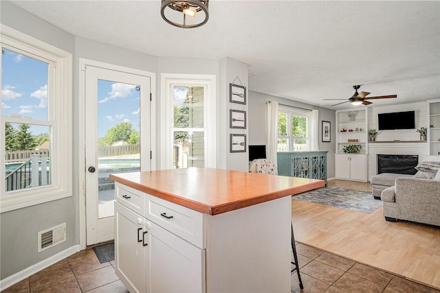 3487 Scenic Way, Walworth, NY 14502 - kitchen featuring a fireplace, tile patterned floors, open floor plan, white cabinetry, and a ceiling fan