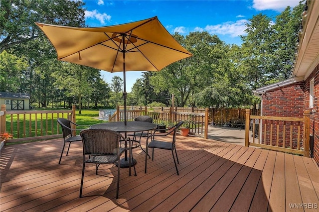 4964 Meadowbrook Rd, Clarence, NY 14221 - wooden terrace with outdoor dining area, a storage shed, and view of wooded area