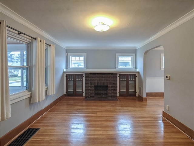120 Whiteford Rd, Rochester, NY 14620 - unfurnished living room featuring arched walkways, wood finished floors, healthy amount of natural light, a brick fireplace, and crown molding