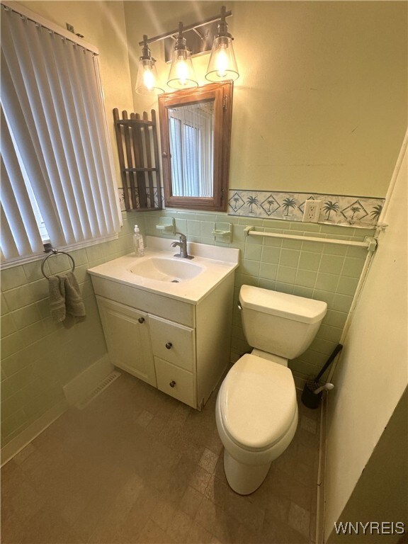 5799 Fairview Dr, Cambria, NY 14132 - half bathroom featuring tile walls, vanity, wainscoting, and healthy amount of natural light