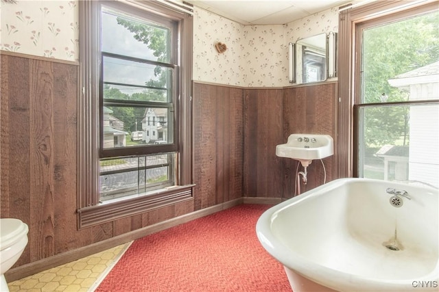14309 Maple St, Diana, NY 13648 - bathroom with wallpapered walls, wainscoting, a soaking tub, and wood walls