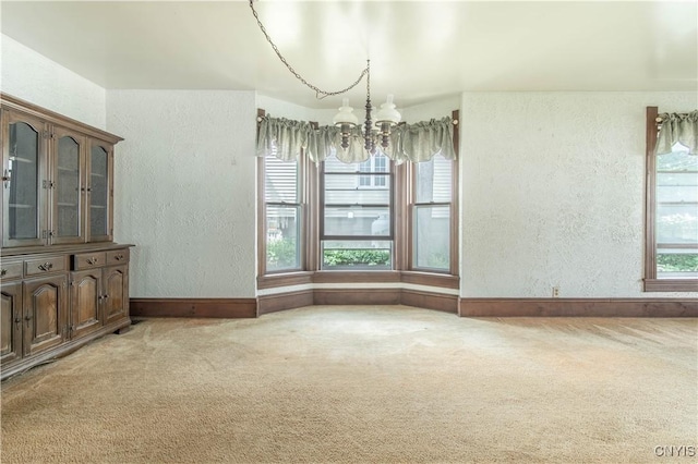 14309 Maple St, Diana, NY 13648 - unfurnished dining area with a chandelier, a textured wall, and light carpet