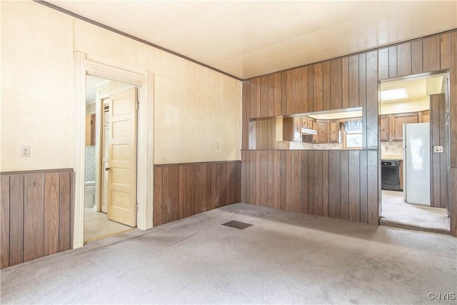 14309 Maple St, Diana, NY 13648 - kitchen featuring freestanding refrigerator, black dishwasher, wooden walls, light colored carpet, and wainscoting